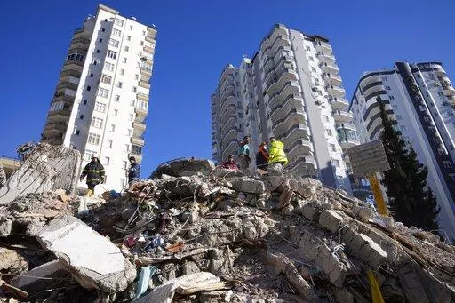 Emergency teams search for people in the rubble of a destroyed building in Adana, southern Turkey, Tuesday, Feb. 7, 2023. The 2011 quake, tsunami and nuclear meltdown in northern Japan provides a glimpse of what Turkey and Syria could face in the years ahead. No two events are alike, but the recent disaster resembles Japan's in the sheer enormity of the psychological trauma, of the loss of life and of the material destruction. (AP Photo/Hussein Malla, File)