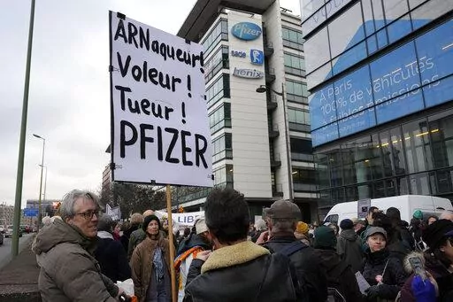 A demonstrator holds a placard reading "Scammer, thief, killer, Pfizer" during a protest against the vaccine pass and vaccinations to protect against COVID-19 in front of the Pfizer headquarters, in Paris, on Jan. 29, 2022. An anti-vaccine group that has harassed doctors and public officials in Italy and France is still active on platforms like Facebook despite efforts to rein in their abuse and misinformation. The organization, known as V_V, bombards its victims with dozens, hundreds or even th