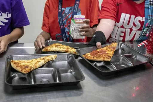 Second-grade students select their meals during lunch break in the cafeteria, Dec. 12, 2022, at an elementary school in Scottsdale, Ariz. More students in schools serving low-income communities will be eligible to receive breakfast and lunch at no cost under a rule change announced Tuesday, Sept. 26, 2023, by the U.S. Department of Agriculture. (AP Photo/Alberto Mariani, File)