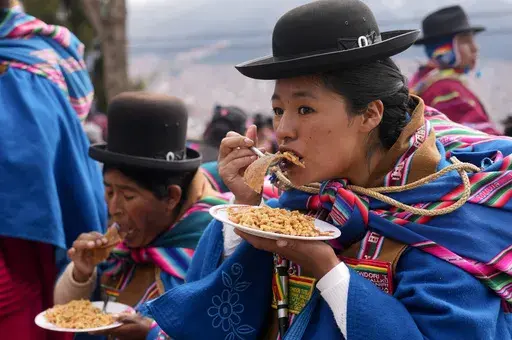 Women eat noodle soup at a street stall in El Alto, Bolivia, Wednesday, March 19, 2025. (AP Photo/Juan Karita)