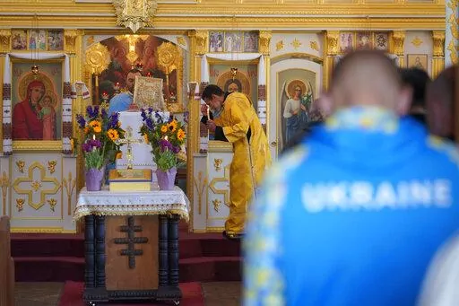 Father Vasile Sauciur, left, and subdeacon David De Jesus, center, hold a service for Ukraine at the Saint Andrew Ukrainian Orthodox Church of Los Angeles Sunday, Feb. 27, 2022. In Los Angeles, where Russians, Ukrainians, Lithuanians and others live, pray, eat and shop together, there's a range of emotions about the invasion of Ukraine. But most palpable is a feeling of solidarity with the Ukrainians under attack by Russian forces. (AP Photo/Damian Dovarganes)