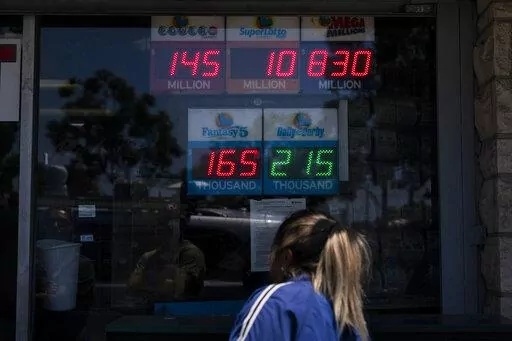 A woman peeks through the window of Blue Bird Liquor while waiting in line to purchase a Mega Millions lottery ticket in Hawthorne, Calif., Tuesday, July 26, 2022. Lottery players will be gripping their tickets tightly ahead of the Tuesday night's Mega Millions drawing with an estimated $830 million prize on the line. AP Photo/Jae C. Hong)