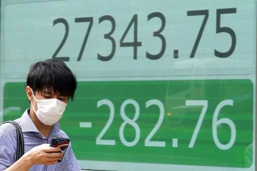 A person wearing a protective mask walks past an electronic stock board showing Japan's Nikkei 225 index at a securities firm Wednesday, Sept. 7, 2022, in Tokyo. Asian shares were mostly lower Wednesday, as pessimism prevailed about higher interest rates ahead and Wall Street shares fell for the fourth straight week. Oil prices fell, while the Japanese yen continued to decline against the U.S. dollar to nearly 144 yen. (AP Photo/Eugene Hoshiko)