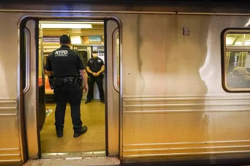 FILE- New York Police Officers with the Transit Bureau Anti Terrorism Unit board a train at the Canal St. Q station, Tuesday, May 24, 2022, in New York. False claims that New York City is experiencing a crime wave -- especially in Manhattan where Trump faces criminal charges - are spreading on social media following a congressional hearing on violence in the city on Monday, April 17, 2023. (AP Photo/Mary Altaffer, File)