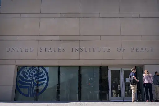 People stand outside the headquarters of the United States Institute of Peace, Tuesday, March 18, 2025, in Washington. (AP Photo/Mark Schiefelbein).