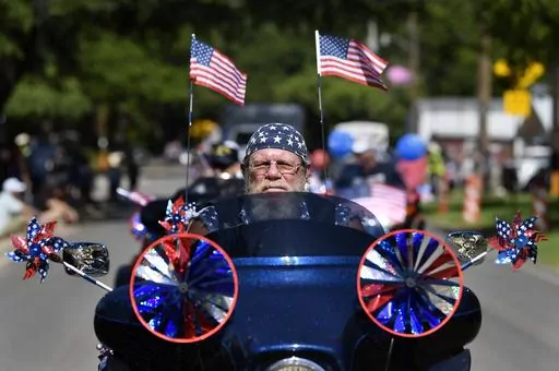 Flags and patriotic stars flutter and twirl as Dwane Tervooren rides with other motorcyclists during Tuesday's Independence Dayparade in Buffalo Gap, Texas Tuesday, July 4, 2023. (Ronald W. Erdrich /The Abilene Reporter-News via AP)