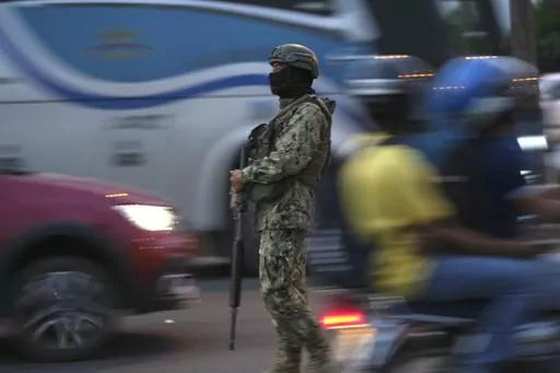 A soldier monitors vehicle traffic on the National Unity Bridge that connects the town of Duran with the Guayaquil, Ecuador, July 20, 2023. Guayaquil is the epicenter of violence. About a third of this year’s violent deaths took place in what is Ecuador’s second-largest city and home to the main commercial port, as well as a large prison complex. (AP Photo/Dolores Ochoa, File)