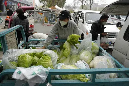 Residents buy fresh vegetables from street vendors as restaurants are closed in some districts in Beijing, Thursday, Nov. 24, 2022. China is expanding lockdowns, including in a central city where factory workers clashed this week with police, as its number of COVID-19 cases hit a daily record. (AP Photo/Ng Han Guan)