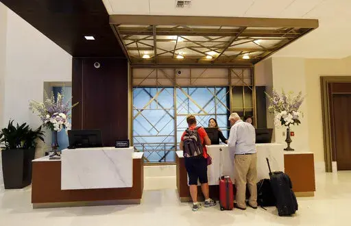 FILE- In this Sept. 5, 2018, file photo guests stand at the front desk at the Embassy Suites by Hilton hotel in Seattle's Pioneer Square neighborhood in Seattle. In the 1990s and early 2000s, hotels began offering 100% Satisfaction Guarantees to customers. The promise ensured that customers who were dissatisfied with their service would be guaranteed full refunds with no questions asked. Fast forward to 2022, and it looks like this prevailing expectation has had a negative impact on the overall 