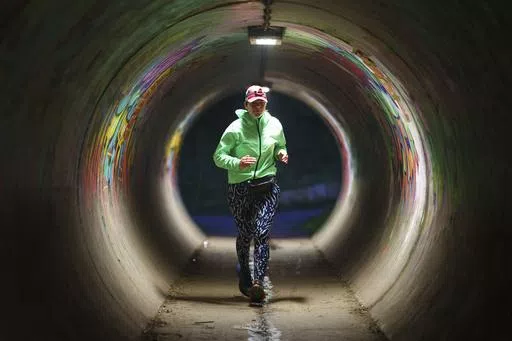 Ultra runner Helen Ryvar runs through an underpass in Wrexham during running a half marathon in Wrexham, Wales, Wednesday, March 20, 2024. Helen who took up running in 2020 just before lockdown completes her daily half marathon early so as to fit in a full time job and being a single parent to 3 children. (AP Photo/Jon Super)