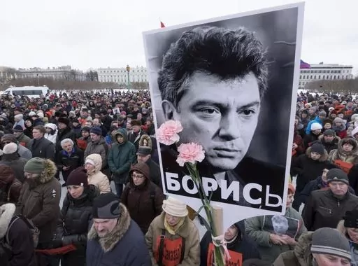 In this Sunday, Feb. 26, 2017 file photo, People gather in memory of opposition leader Boris Nemtsov, portrait in center, in St. Petersburg, Russia. Once deputy prime minister under Boris Yeltsin, Nemtsov was a popular politician and harsh critic of Putin. On a cold February night in 2015, he was gunned down by assailants on a bridge adjacent to the Kremlin as he walked with his girlfriend in a death that sent shockwaves across the country. (AP Photo/Dmitri Lovetsky, file)