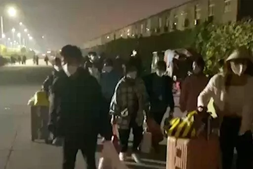 In this photo taken from video footage and released by Hangpai Xingyang, people with suitcases and bags are seen leaving from a Foxconn compound in Zhengzhou in central China's Henan Province on Saturday, Oct. 29, 2022. Workers in a Foxconn facility in the central Chinese city of Zhengzhou appear to have left the facility to avoid COVID-19 curbs, with many traveling by foot days after an unknown number of factory workers were quarantined in the facility following a virus outbreak. (Hangpai Xingy