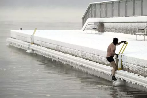 A man climbs out from the icy sea to the pier, in southern Helsinki, Finland, Tuesday, Jan. 2, 2024. Finland and Sweden have recorded this winter’s cold records on Tuesday as a temperatures plummeted to over minus 40 degrees as a result of a cold spell prevailing in the Nordic region. (Vesa Moilanen/Lehtikuva via AP)