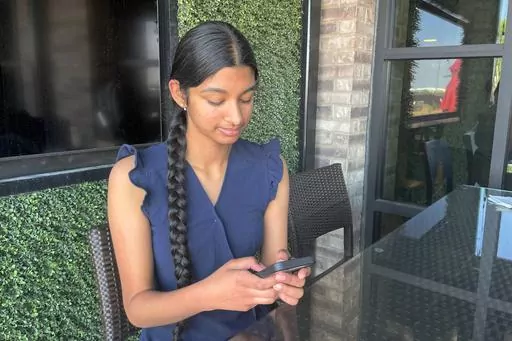 Shreya Nallamothu looks at her phone in Bloomington, Ill., on Tuesday, May 9, 2023. Illinois lawmakers aim to make their state what they say will be the first in the country to create protections for child social media influencers. Nallamothu, 15, raised her concerns to Illinois state Sen. David Koehler of Peoria, who then set the legislation in motion. (AP Photo/Claire Savage)
