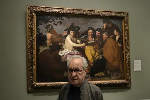 Novelist John Banville poses by Diego Velazquez's 'The Feast of Bacchus' at the Prado Museum in Madrid, Spain, Wednesday, Oct. 23, 2024. (AP Photo/Paul White)