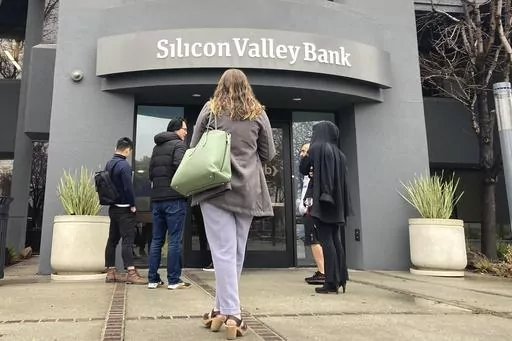 People stand outside a Silicon Valley Bank branch in Santa Clara, Calif., Friday, March 10, 2023. The Federal Reserve is scheduled Friday to release a highly-anticipated review of its supervision of Silicon Valley Bank, the go-to bank for venture capital firms and technology start-ups that failed spectacularly in March. (AP Photo/Jeff Chiu, File)