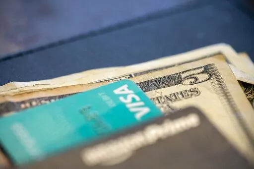 In this Aug. 11, 2019 file photo, U.S. currency and credit cards sit on a table at a restaurant in New Orleans. With inflation at 7.1% in November, it’s not surprising that savings aren’t going as far as they used to. Part-time gigs like tutoring, pet sitting or helping with tax prep allow retirees to work a few hours at a time, and the extra income can make a big differenc(AP Photo/Jenny Kane, File)