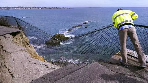 Public Services Director Bill Riccio peers down at debris along the historic Cliff Walk, Tuesday, March 15, 2022, in Newport, R.I. A roughly 30-foot section of the walk crumbled into the sea last week, leaving officials to ponder whether to rebuild or let if continue to fall into the ocean. (AP Photo/Charles Krupa)