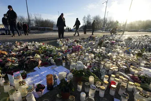 People gather at a makeshift memorial near the scene of a shooting on the outskirts of Orebro, Sweden, Friday, Feb. 7, 2025. (AP Photo/Sergei Grits)
