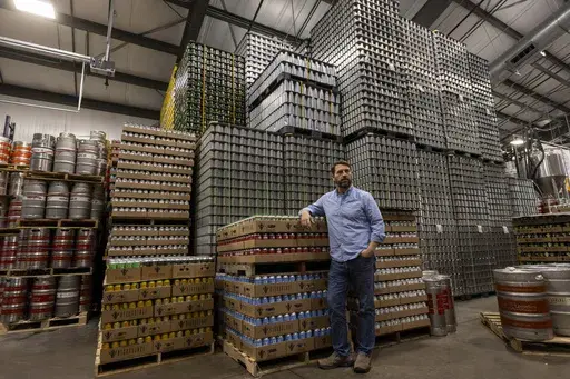 Jeff Ware, president of Resurgence Brewing Company, poses for a portrait near a stockpile of aluminum cans, which are sourced from Canada, Thursday, Feb. 27, 2025, in Buffalo, N.Y. (AP Photo/Lauren Petracca)