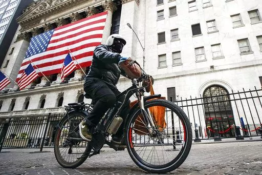 A delivery worker rides his electric bicycle past the New York Stock Exchange, March 16, 2020, in New York.Lithium ion batteries used to power electric bicycles and scooters have already sparked 22 fires that caused 36 injuries and two deaths in New York City this year, four times the number of fires linked to the batteries by this time last year, city officials said Friday, Feb. 24, 2023. (AP Photo/John Minchillo, File)