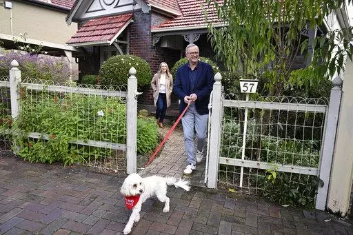 Australia's Prime Minister-elect Anthony Albanese, right, and his partner Jodie Haydon go for a walk with their dog, Toto, in Sydney, Sunday, May 22, 2022. Albanese has promised to rehabilitate Australia's international reputation as a climate change laggard with steeper cuts to greenhouse gas emissions. (Dean Lewins/AAP Image via AP)