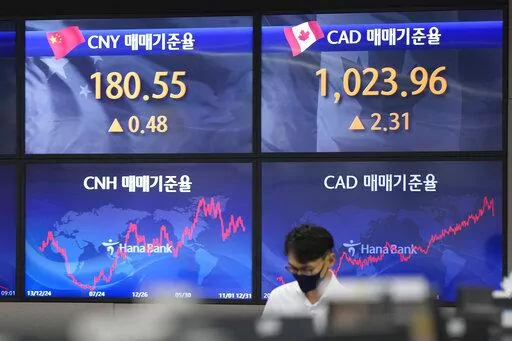 A currency trader walks near the screens showing the foreign exchange rates at a foreign exchange dealing room in Seoul, South Korea, Tuesday, Oct. 11, 2022. Asian shares were mostly lower on Tuesday as losses in technology-related shares weighed on global benchmarks.(AP Photo/Lee Jin-man)