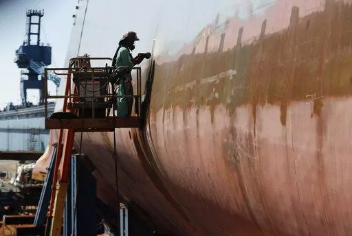 FILE — Welder Neal Larsen works on the hull of a Zumwalt-class destroyer Aug. 29, 2018, being built in the shipyard at Bath Iron Works in Bath, Maine. The U.S. Navy, following costly lessons after cramming too much new technology onto warships and speeding them into production, is slowing down the design and purchase of its next-generation destroyer, and taking extra steps to ensure new technology like lasers and hypersonic missiles have matured before pressing ahead. (AP Photo/Robert F. Bukat