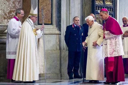 Pope Francis, second from left, watches Pope Emeritus Benedict XVI enter St. Peter's Basilica accompanied by Monsignor Georg Gaenswein, right, at the Vatican, on Dec. 8, 2015. Pope Benedict XVI's 2013 resignation sparked calls for rules and regulations for future retired popes to avoid the kind of confusion that ensued. Benedict, the German theologian who will be remembered as the first pope in 600 years to resign, has died, the Vatican announced Saturday Dec. 31, 2022. He was 95. (AP Photo/Andr