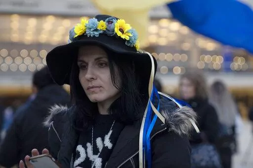 A woman wears a flower crown in the colors of the Ukranian flag in Habima Square in Tel Aviv, Israel, to watch Ukrainian President Volodymyr Zelenskyy in a video address to the Knesset, Israel's parliament, Sunday, March 20, 2022. (AP Photo/Maya Alleruzzo)