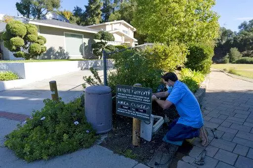 CORRECTS SPELLING TO AGOURA HILLS NOT AGORA HILLS Cason Gilmer, a senior field customer service representative from the Las Virgenes Municipal Water District, installs an advanced water metering system in Agoura Hills , Calif., Wednesday, Jan. 5, 2022. The wealthy enclave along the Santa Monica Mountains that is haven for celebrities has taken aggressive steps to try to limit water use during California's drought, including lowering the thresholds for fines for those who go over their "water bud