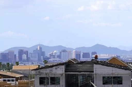 In this Aug. 12, 2021, file photo with the downtown skyline in the background, a roofer works on a new home being built in a new housing development as expansive urban sprawl continues in Phoenix. Some of the largest U.S. cities challenging their 2020 census numbers aren't getting the results they hoped for from the U.S. Census Bureau. (AP Photo/Ross D. Franklin, File)