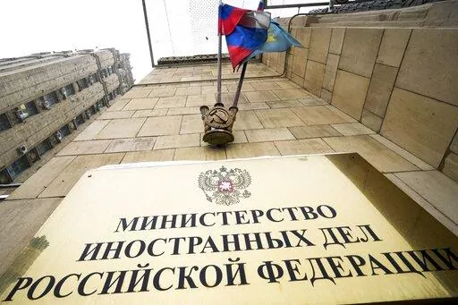 A Russian national flag flutters in the wind next to the sign of the Russian Foreign Ministry building in Moscow, Russia, Wednesday, Jan. 26, 2022. Russian Foreign Minister Sergey Lavrov said he and other top officials will advise President Vladimir Putin on the next steps after receiving written replies from the United States to the demands. Those answers are expected this week — even though the U.S. and its allies have already made clear they will reject the top Russian demands. (AP Photo/Al