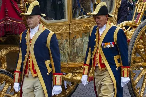 FILE- Footmen walk alongside the Golden Carriage as Netherlands' King Willem-Alexander and Queen Maxima arrive at Noordeinde Palace, after the King officially opened the new parliamentary year in The Hague, Netherlands, Tuesday Sept. 17, 2013. The Dutch king ruled out Thursday, Jan. 13, 2022, using in the near future the royal family's Golden Carriage, one side of which is decorated with a painting, center, that has drawn fire from critics who say it glorifies the Netherlands' colonial past, inc