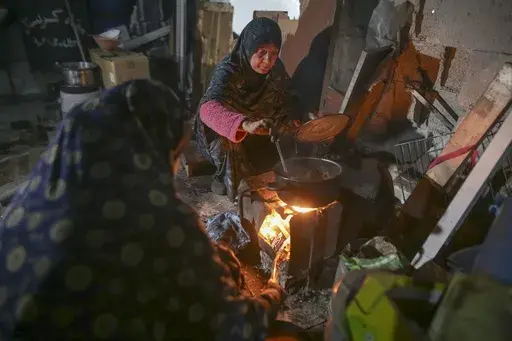 Fatima Al-Absi prepares food for her family's iftar, the fast-breaking meal, on the first day of Ramadan in their damaged apartment in Jabaliya, northern Gaza Strip, on Saturday, March 1, 2025. (AP Photo/Jehad Alshrafi)