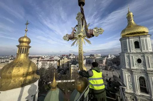 Ihor Kuzmenko, altitude worker installs a restored cross on a dome of Saint Sophia Cathedral in Kyiv, Ukraine, Thursday, Dec. 21, 2023. A UNESCO World Heritage site, the gold-domed St. Sophia Cathedral, located in the heart of Kyiv, was built in the 11th century and designed to rival the Hagia Sophia in Istanbul. The monument to Byzantine art contains the biggest collection of mosaics and frescoes from that period, and is surrounded by monastic buildings dating back to the 17th century. (AP Phot