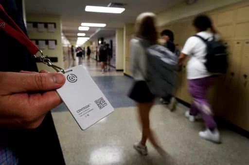 Brent Kiger, Olathe Public Schools' director of safety service, displays a panic-alert button while students at Olathe South High School rush between classes, Aug. 19, 2022, in Olathe, Kan. The district introduced the buttons, which allow staff to trigger a lockdown that will be announced with flashing strobe lights, a takeover of staff computers and a prerecorded intercom announcement, at the start of this school year as part of $2.1 million plan to make district schools more secure. In the wak
