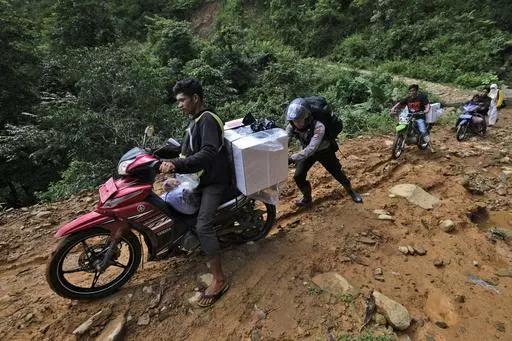 A police officer assists an electoral worker to drive his motorbike up a hill as they distribute ballot boxes and other election paraphernalia to polling stations in remote villages ahead of the Feb. 14 election in Maros, Indonesia, Tuesday, Feb. 13, 2024. Indonesia, the world's third-largest democracy, will open its polls on Wednesday to nearly 205 million eligible voters in presidential and legislative elections, the fifth since Southeast Asia's largest economy began democratic reforms in 1998