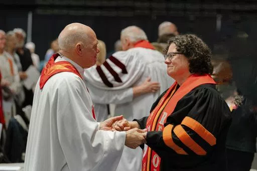 In this photo provided by the United Methodists of Eastern Pennsylvania, Rev. Dr. Beth Stroud, right, holds hands with Bishop John Schol after offering a prayer of blessing at the Wildwoods Convention Center, Wildwood, N.J., on Tuesday, May 21, 2024, as he prepares to retire in August. Twenty years ago, Stroud was defrocked as a pastor after telling her congregation that she was in a committed same-sex relationship. On Tuesday night, less than three weeks after the UMC repealed its anti-LGBTQ ba