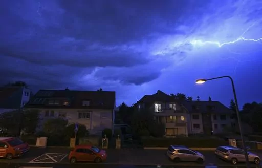 In this shot with slow shutter speed, lightning discharges in the evening sky during a heavy thunderstorm over the houses in the district of Sachsenhausen, Frankfurt/Main, Germany Wednesday, Aug. 16, 2023. Heavy rain in parts of Germany caused flooding and led to dozens of flight cancelations at Frankfurt Airport, the country's busiest and a major European hub, authorities said Thursday. (Arne Dedert/dpa via AP)