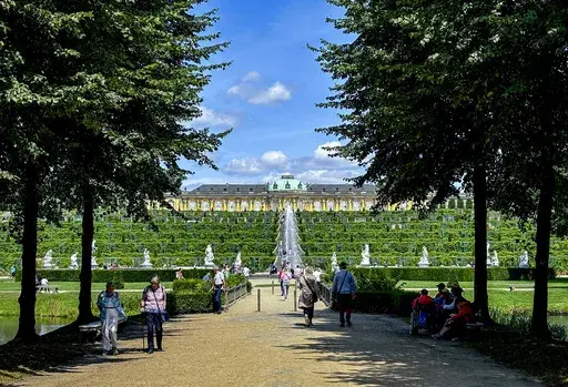 People walk in the park of the Sanssouci Palace in Potsdam, Germany, Thursday, July 25, 2024. Germany's Sanssouci Park seeks solutions as its trees struggle with climate change. (AP Photo/Geir Moulson)