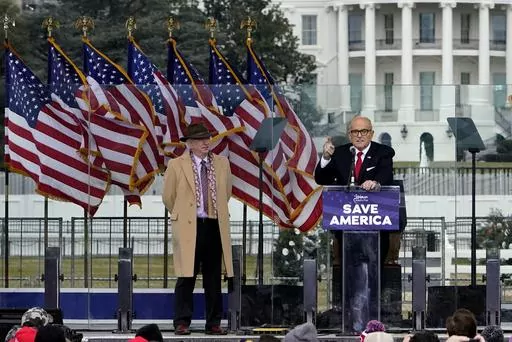 Chapman University law professor John Eastman stands at left as former New York Mayor Rudolph Giuliani speaks in Washington at a rally in support of President Donald Trump, called the "Save America Rally" on Jan. 6, 2021. The 18 defendants charged alongside Trump in this month's racketeering indictment in Fulton County include more than a half-dozen lawyers, and the statements from Eastman and Giuliani provide early foreshadowing of at least one of the defenses they seem poised to raise: that th
