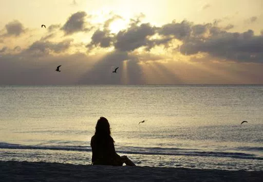 A woman meditates on the beach in Miami Beach, Fla., on April 28, 2010. Research shows a daily meditation practice can reduce anxiety, improve overall health and increase social connections, among other benefits. (AP Photo/Lynne Sladky, File)