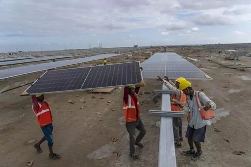 Workers install solar panels at the under-construction Adani Green Energy Limited's Renewable Energy Park in the salt desert of Karim Shahi village, near Khavda, Bhuj district near the India-Pakistan border in the western state of Gujarat, India, Thursday, Sept. 21, 2023. Nations have signed on to triple renewable energy by 2030. (AP Photo/Rafiq Maqbool)