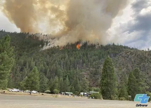 In this photo provided by Caltrans, smoke rises from the Head Fire in Klamath National Forest, Calif., on Tuesday Aug. 15, 2023. A wildfire pushed by gusty winds from a thunderstorm raced through national forest land near California's border with Oregon, prompting evacuations in the rural area. The blaze in Siskiyou County was one of at least 19 fires that erupted in the Klamath National Forest as thunderstorms rolling through the area brought lightning and downdrafts that drove the flames throu
