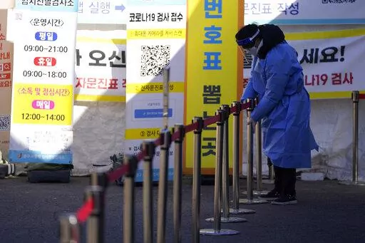 A health worker wearing protective gear prepares for visitors in the sub-zero temperatures at a temporary screening clinic for the coronavirus in Seoul, South Korea, Friday, Jan. 14, 2022. (AP Photo/Lee Jin-man)