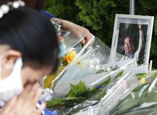 A photo of former Prime Minister Shinzo Abe is displayed on a makeshift memorial near the scene where Abe was fatally shot while delivering his speech to support a Liberal Democratic Party's candidate on Friday, in Nara, Saturday, July 9, 2022.  (Yosuke Mizuno/Kyodo News via AP)