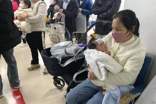A woman tends to a child at the fever clinic of a Children's hospital in Beijing, Wednesday, Dec. 14, 2022. China's National Health Commission scaled down its daily COVID-19 report starting Wednesday in response to a sharp decline in PCR testing since the government eased antivirus measures after daily cases hit record highs. (AP Photo/Dake Kang)
