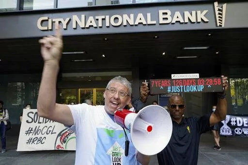 Adam McKay, left, director of the film "Don't Look Up," joins members of the Youth Climate Los Angeles coalition and others protesting climate change outside City National Bank in Los Angeles, Friday, March 18, 2022. On Tuesday Sept. 20, 2022, McKay announced a $4 million donation to the Climate Emergency Fund, an organization dedicated to getting money into the hands of activists engaged in disruptive, nonviolent demonstrations urging swifter action on climate change. (AP Photo/Damian Dovargane