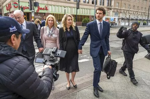 Theranos founder and CEO Elizabeth Holmes, center, walks into federal court in San Jose, Calif., Nov. 18, 2022. Holmes is citing her recently born child as another reason she should be allowed to delay the start of a more than 11-year prison sentence while her lawyers appeal her conviction for duping investors about the capabilities of her failed company's blood-testing technology. The birth of Holmes' second child was confirmed in court documents filed Thursday, Feb. 23, 2023, in advance of a M